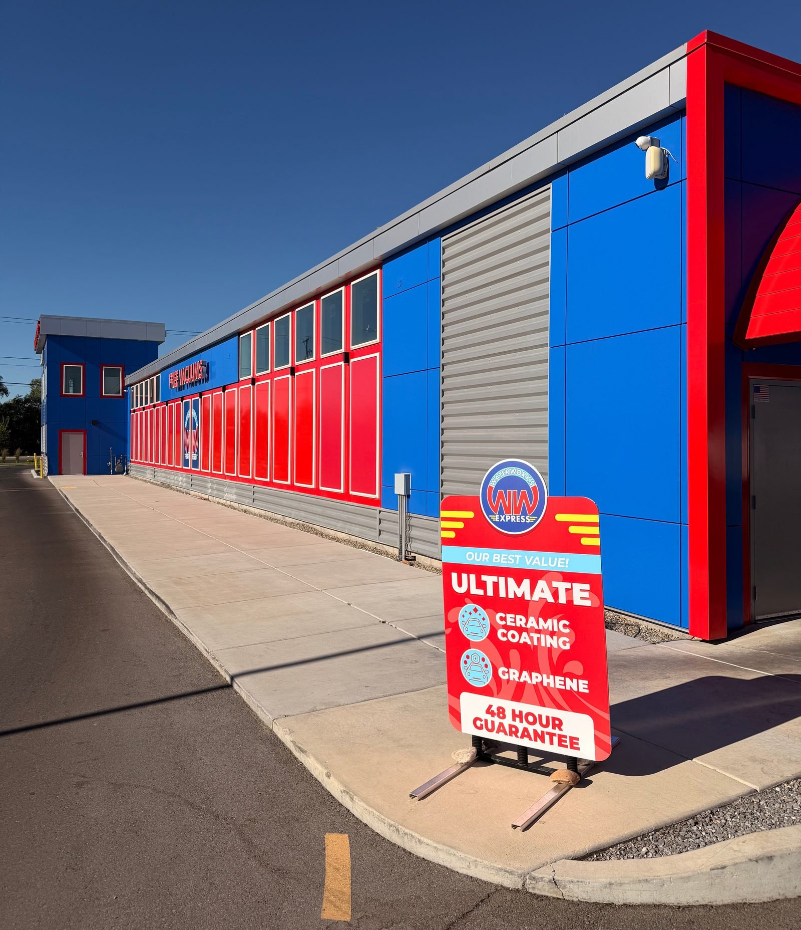 The side of the WaterWorks Express building on 7800 South, with a FREE VACUUMS sign and a forecourt sign advertising the Ultimate wash with ceramic coating, graphene and a 48-hour guarantee.