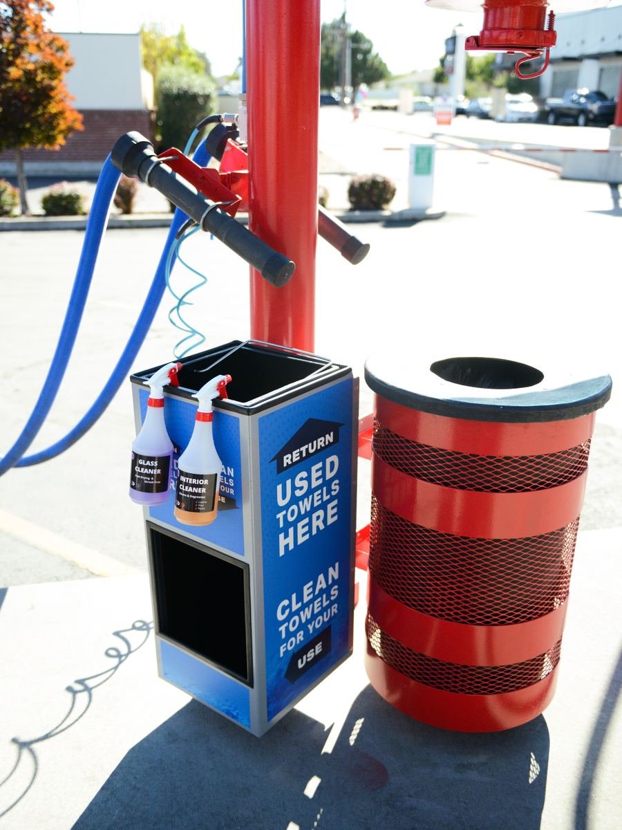 Vacuum and air hoses beside spray bottles of glass cleaner and interior cleaner, and a bin marked clean towels for your use, at WaterWorks Express 9000 South.
