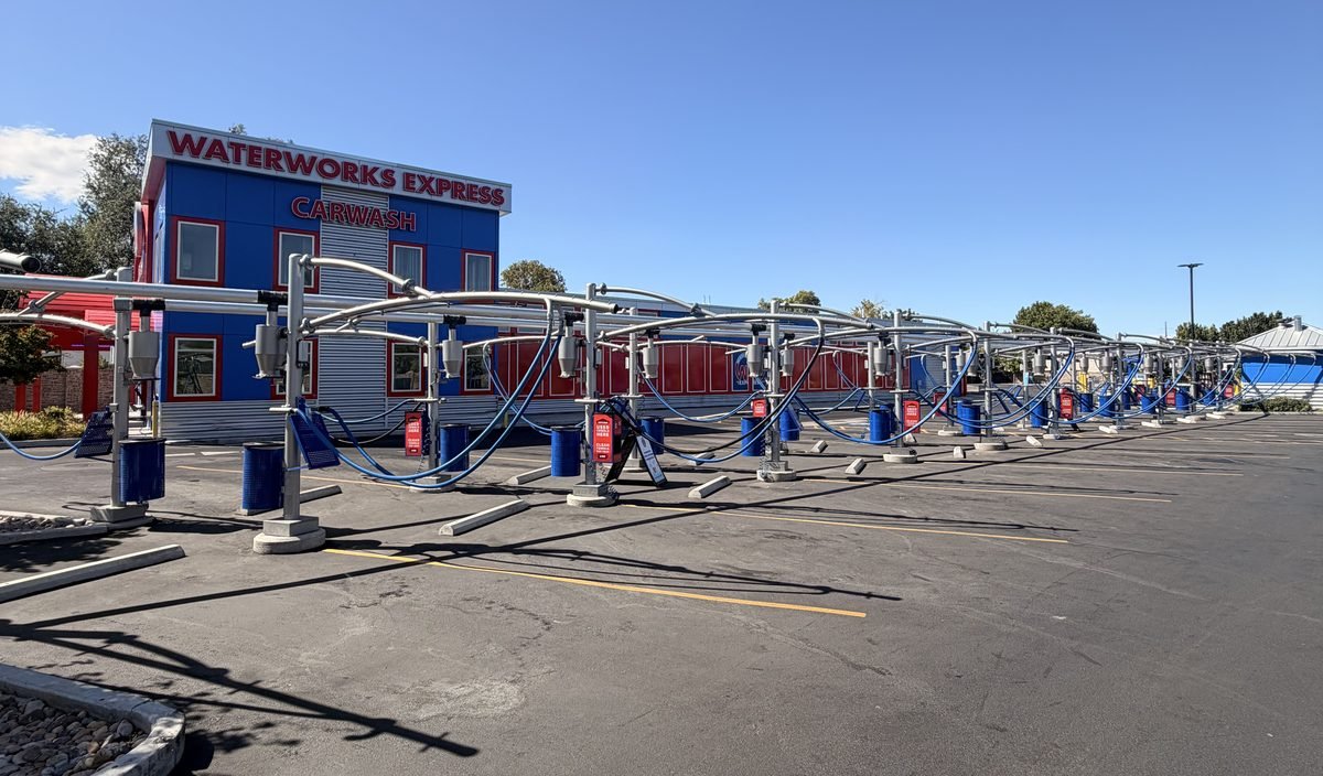 The row of free self-serve vacuum stalls at WaterWorks Express 7800 South, each with its own hose and waste bin, running the length of the lot beside the building.